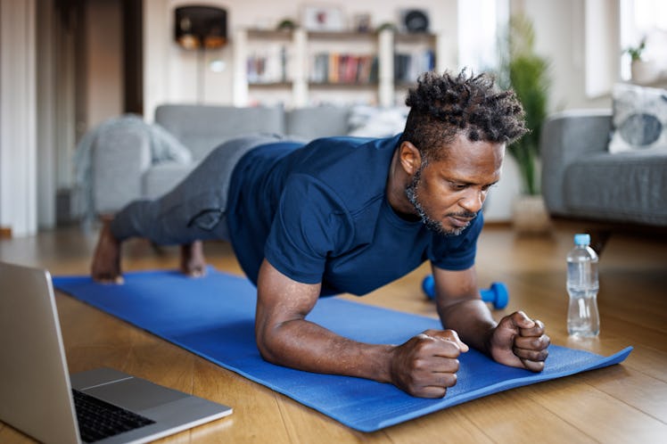 A man doing a plank to burn belly fat on a yoga mat at home.