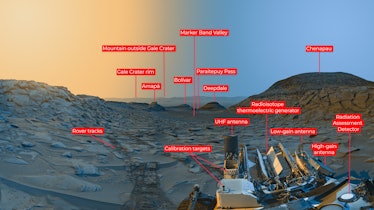 color image of a valley on Mars, with yellow sky on the left and blue sky on the right, and a rover ...