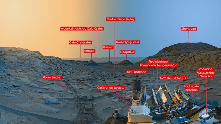 color image of a valley on Mars, with yellow sky on the left and blue sky on the right, and a rover ...