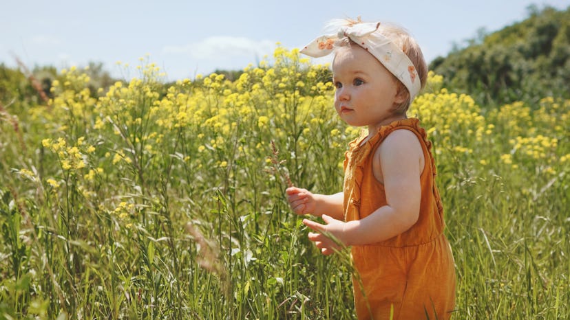 A little girl stands in a field of flowers. Gaia is a unique alternative if you like the name Luna.