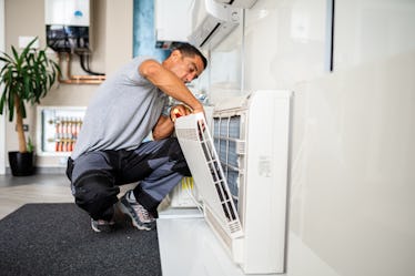 A dad fixes an air conditioner filter at home.