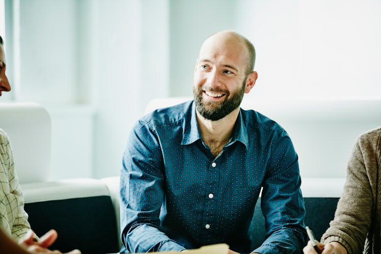 Smiling man sitting in meeting and listening