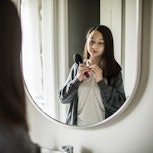 A teen looks at their body in the mirror.