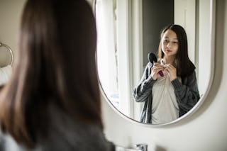 A teen looks at their body in the mirror.