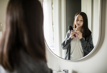 A teen looks at their body in the mirror.