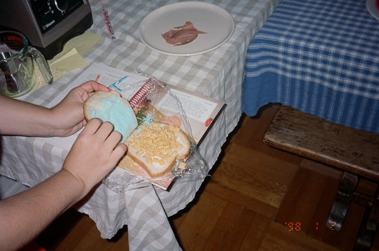 two hands putting together a sandwich made from wonder bread, pixy sticks and sugar cereal at the ed...