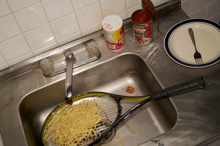 a tennis racket covered in spaghetti in a kitchen sink