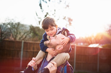 Young boy riding on dad's shoulders in the sunlight