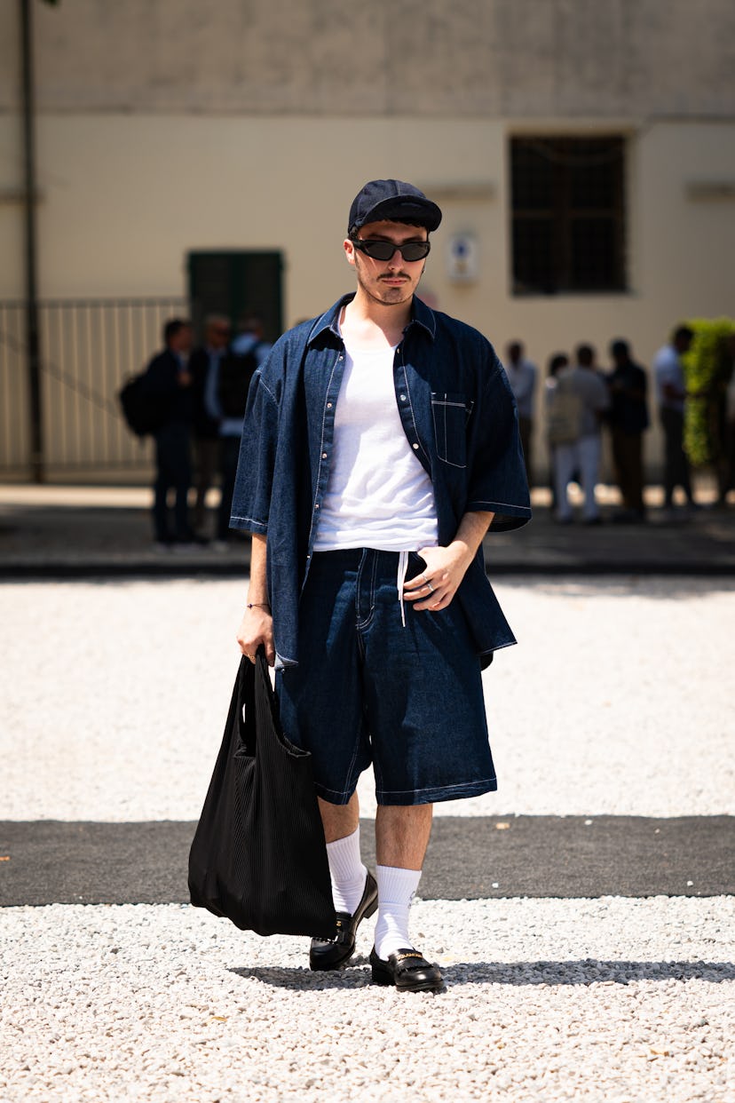A guest, wearing white shirt and blue denim shorts pants, shirt and cap, is seen at Fortezza Da Bass...