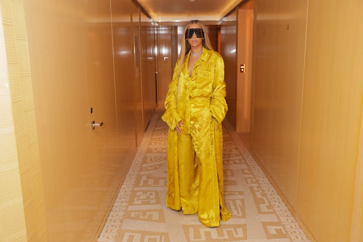 Beyoncé in a hallways wearing a bright yellow silky outfit