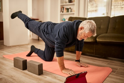 A man at home on a yoga mat doing glute kickbacks.