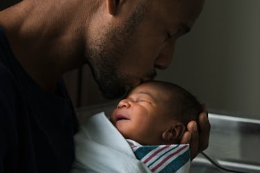 A father kissing his newborn baby on the head.