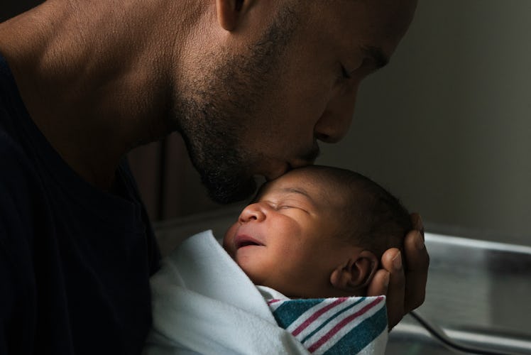 A father kissing his newborn baby on the head.