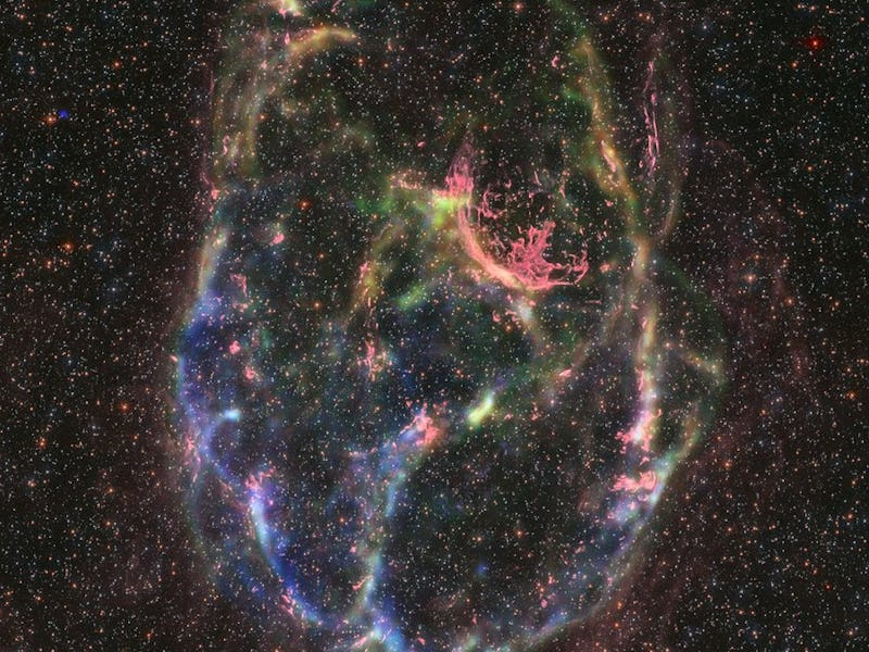 A ring of material contrasts against the background stars and galaxies that are peppered behind it. ...
