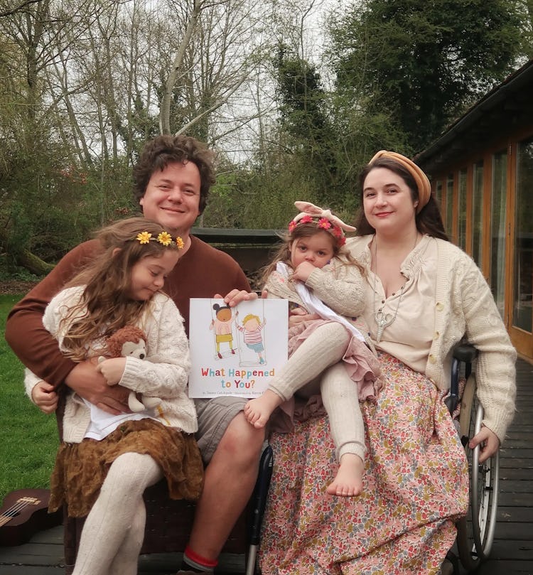 James and Lucy Catchpole with their two daughters on their laps, posing with James' book 'What Happe...