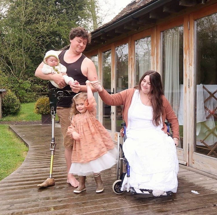 James standing with 'robot leg', holding their youngest daughter as a baby, with their eldest daught...