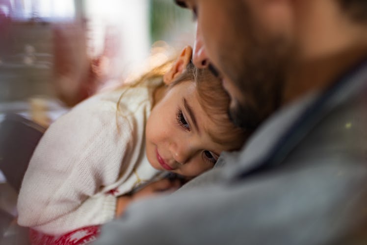 A child resting her head on her father's chest.