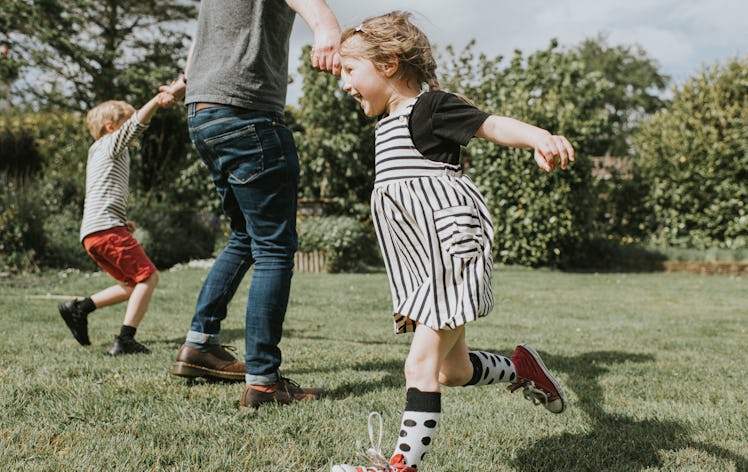 A dad spinning his two kids in the backyard.