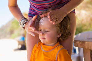 Mom applies sunscreen to child's face