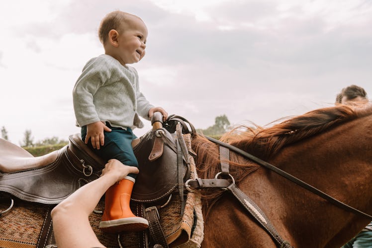 A baby sitting on a horse.