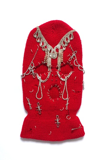 a red ski mask decorated with silver and gold jewelry