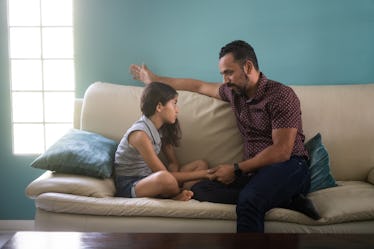 A dad talking to his daughter on a couch.