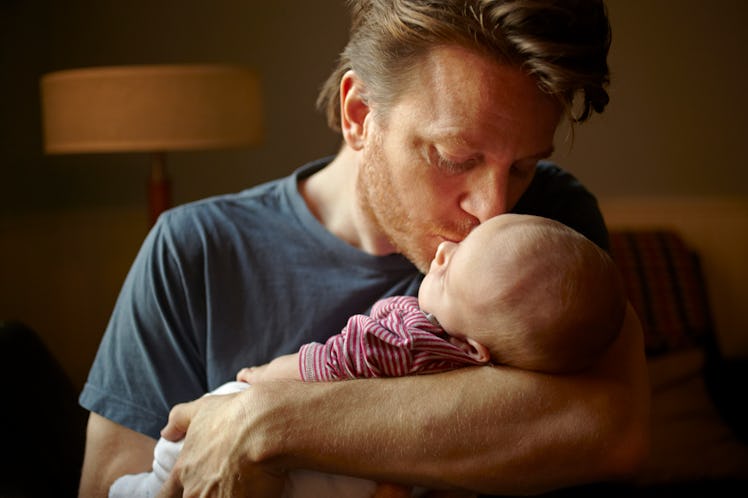 A dad kissing his newborn baby on the head.