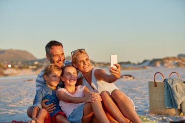 Family of four on beach taking selfie