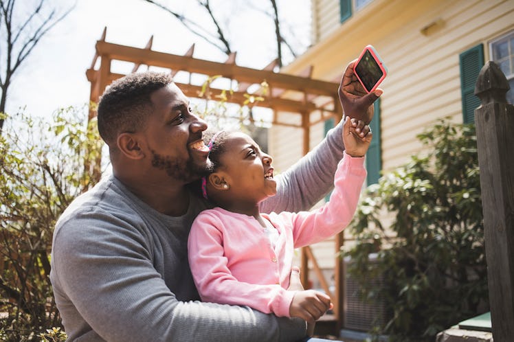 A dad and daughter taking a selfie together.