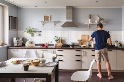 Adult man cooking in kitchen with his back towards the camera