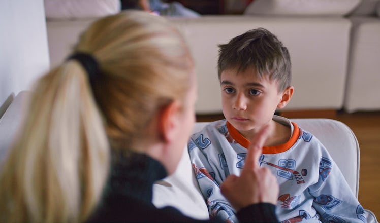A mother lecturing her son as they sit on a sofa.