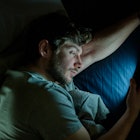 A man on his phone at night in bed.