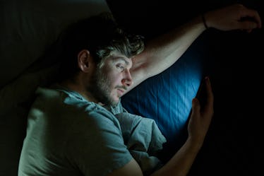 A man on his phone at night in bed.