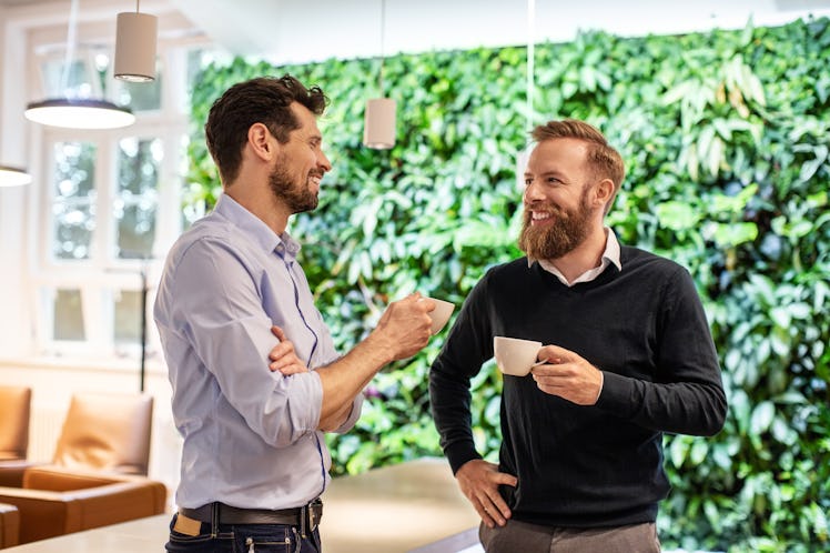 Two adult men drinking coffee and talking