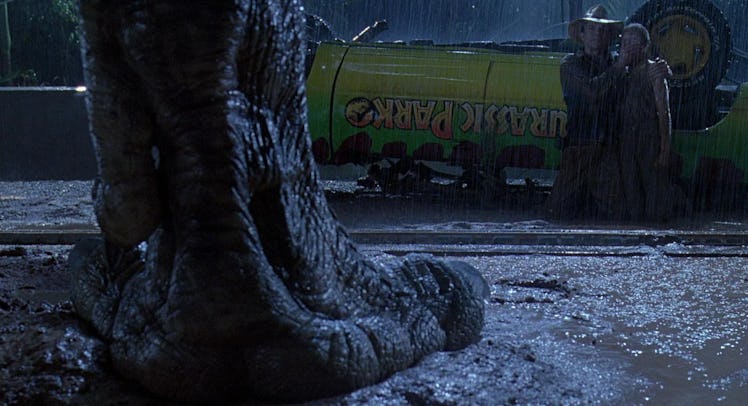 Dr. Alan Grant and Lex Murphy kneel in front of a T-Rex's foot in Jurassic Park