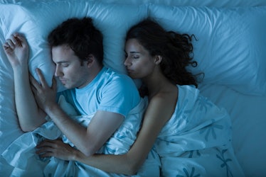 A man and woman cuddling and sleeping in bed.