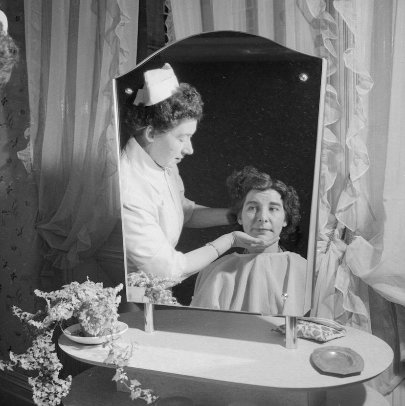 July 1958: Nurse Phyllis Parsonage prepares a patient for some beauty treatment at Saint Matthew's H...
