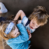 Two children fighting on a couch.