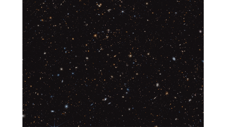 a black background spangled with faint stars and tiny galaxies