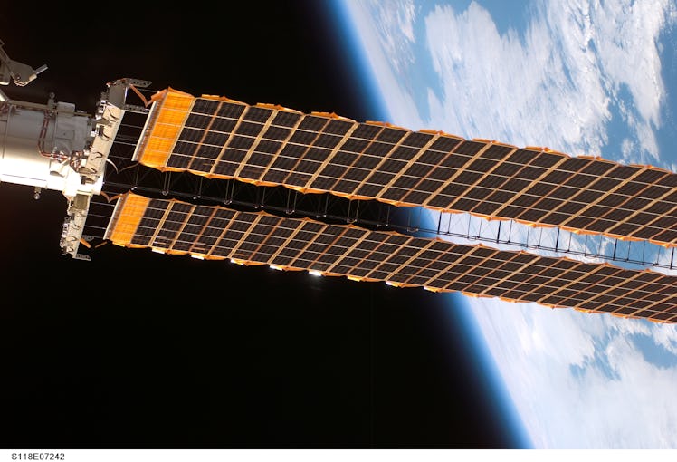 photo of one wing of the space station's solar arrays with Earth in the background