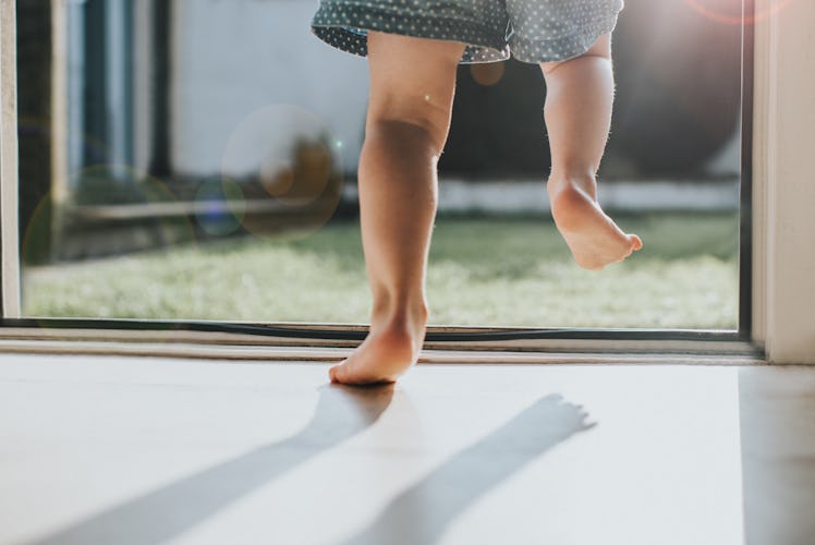 Close up on the legs and feet of a toddler walking on their toes.