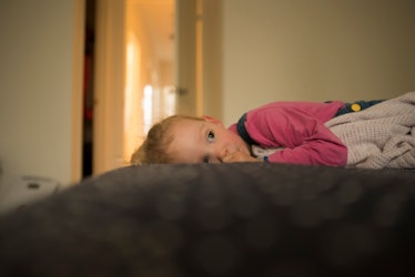 A child lying in bed, covered by a blanket.