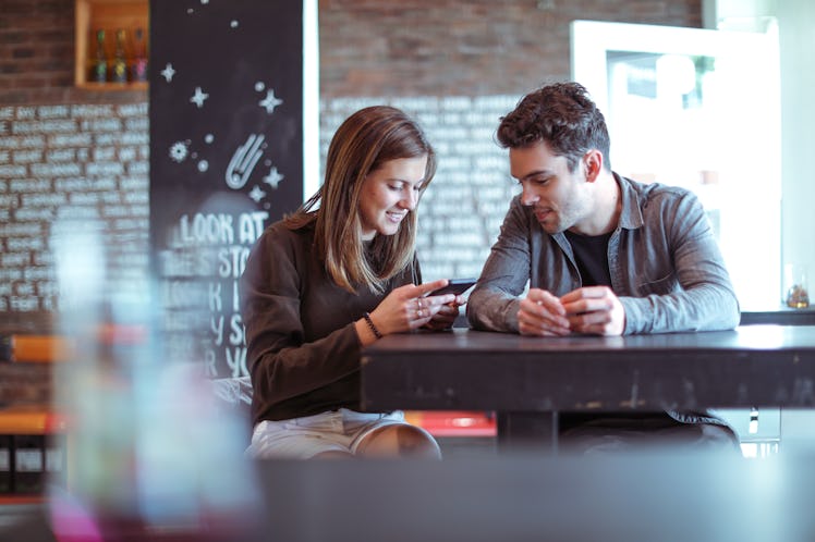 Couple on date night smiling at asking one another questions at bar