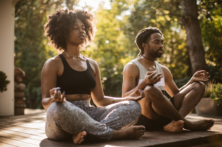 A man and woman meditating outdoors.