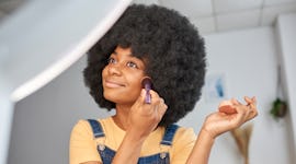 Young woman applying a budget-friendly foundation.