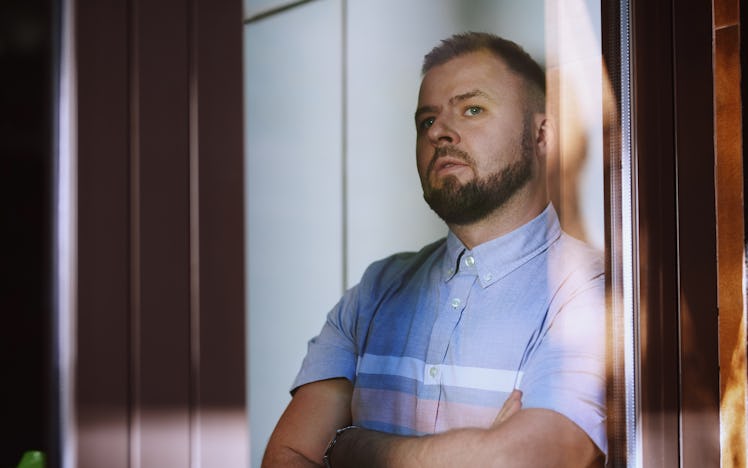 Man standing with arms crossed and looking contemplative