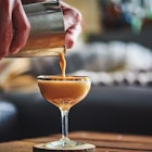 Close-up of an espresso martini being poured from a shaker into a coupe glass