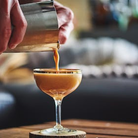 Close-up of an espresso martini being poured from a shaker into a coupe glass