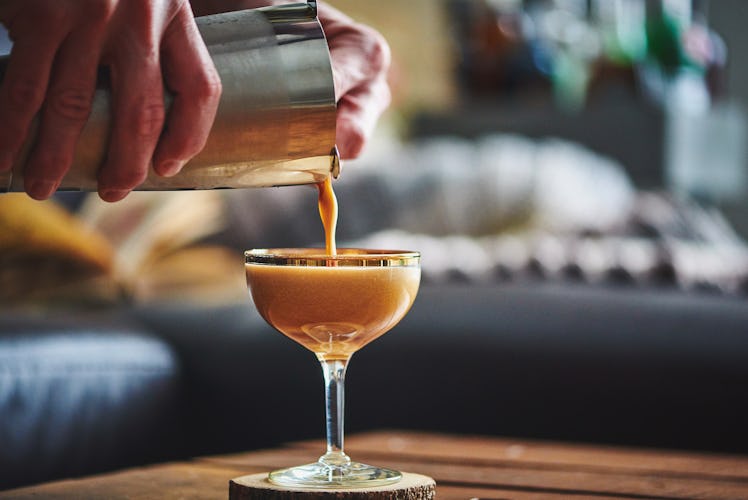 Close-up of an espresso martini being poured from a shaker into a coupe glass