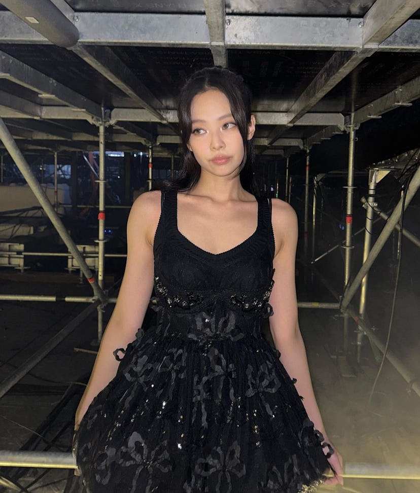Jennie Kim of Blackpink wears a black embroidered Simone Rocha mini dress and Chanel leg warmers.